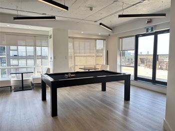 A pool table in a room with a view of the outside.